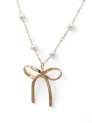 Gold bow pendant necklace with pearls on a white background