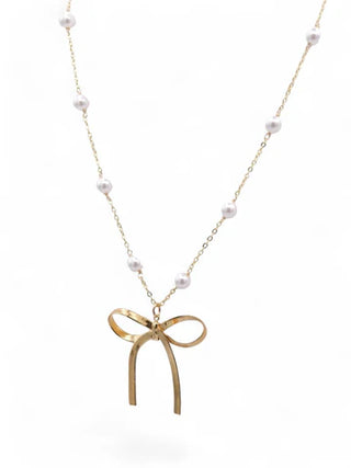 Gold bow-shaped pendant necklace with small pearls on a white background