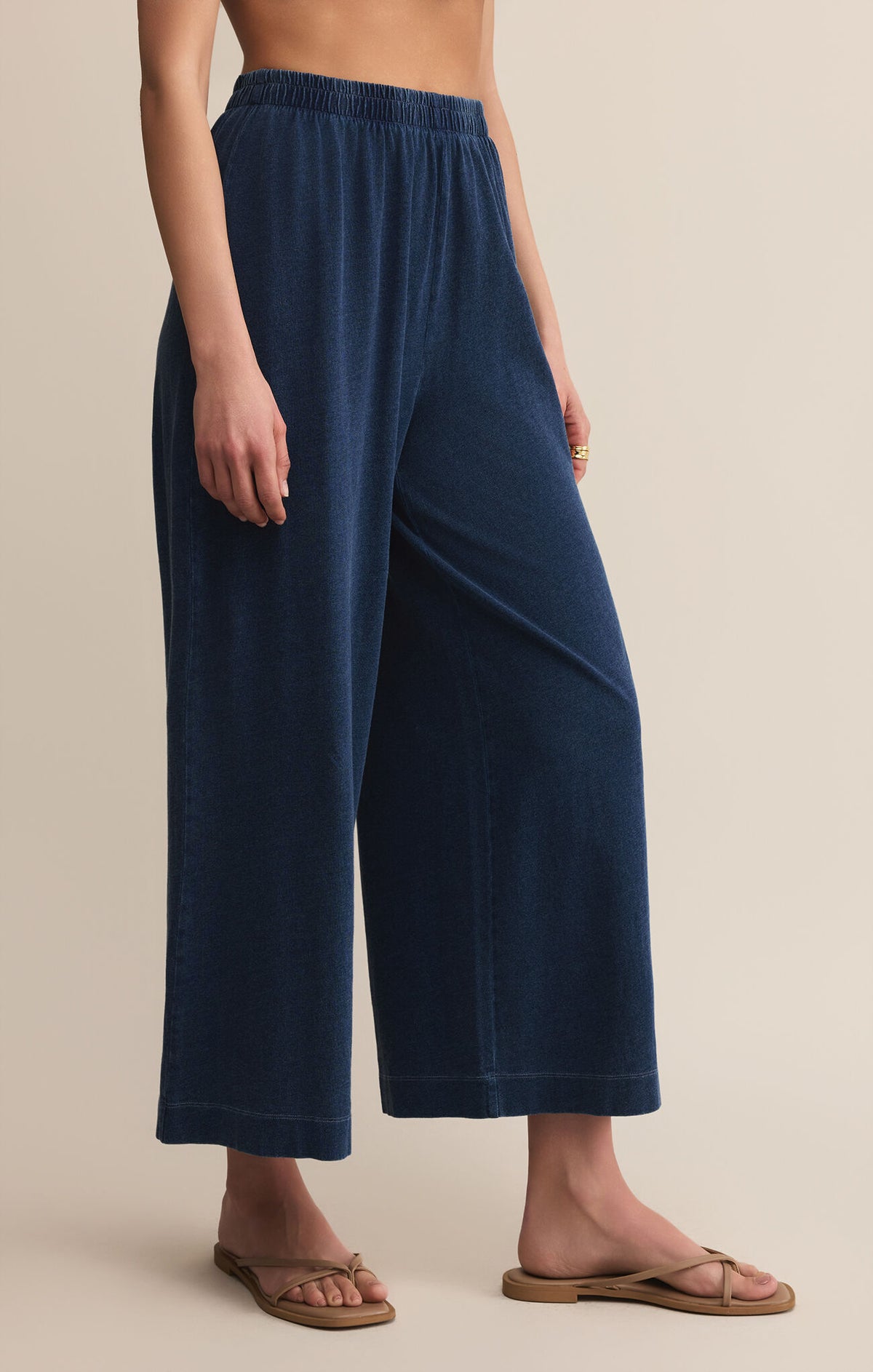 Navy blue wide-leg pants worn by a person on a beige background