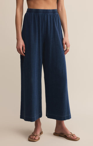 Navy blue wide-leg pants worn by a person on a beige background