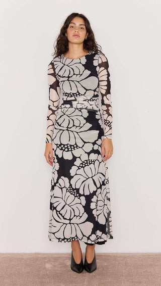 Woman wearing a long floral dress against a plain background