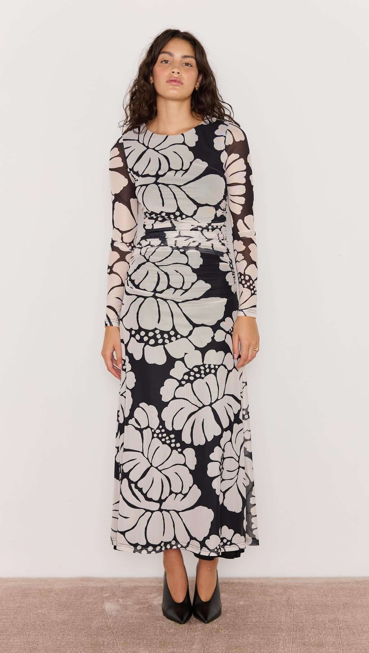 Woman wearing a long floral dress against a plain background