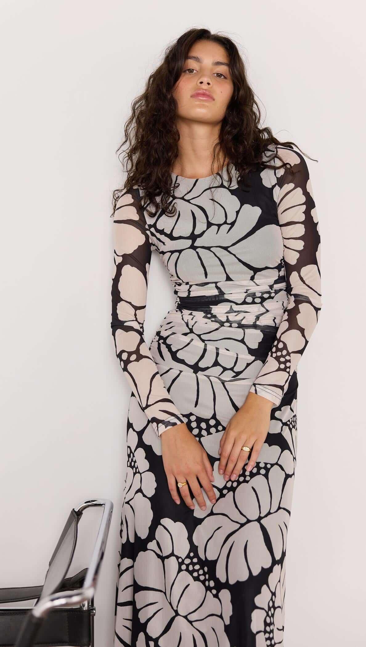 Woman wearing a black and white floral dress against a plain background