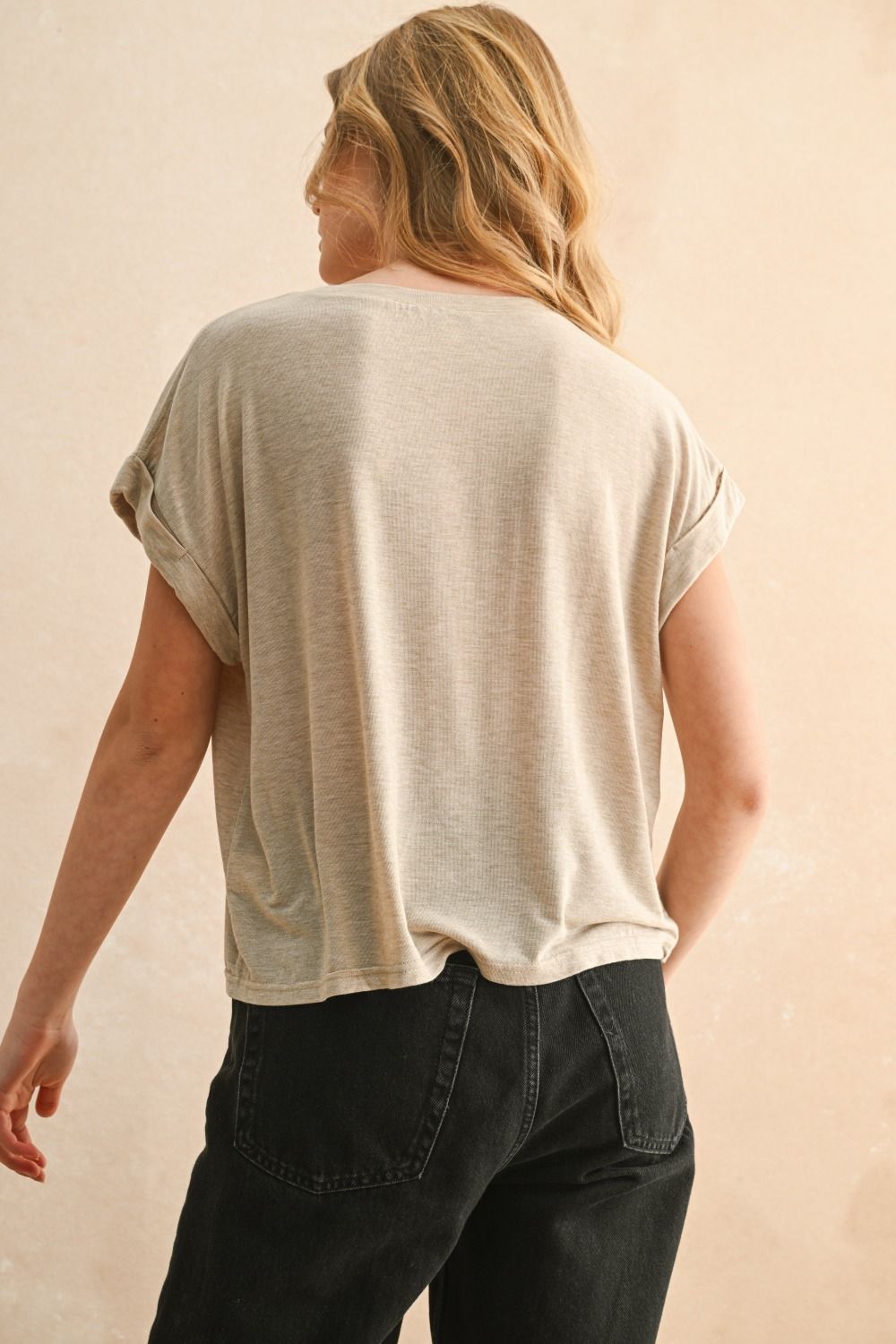 Person wearing a beige t-shirt and dark jeans 