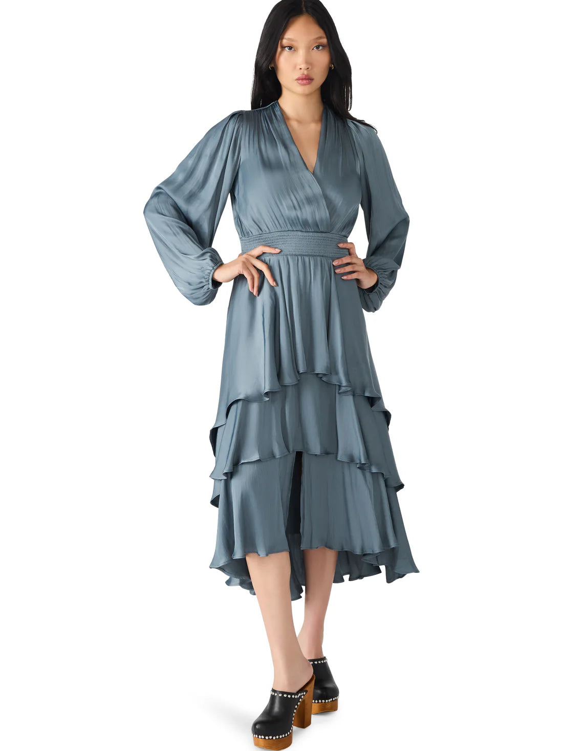 Woman wearing a blue dress with long sleeves and layered skirt on a white background