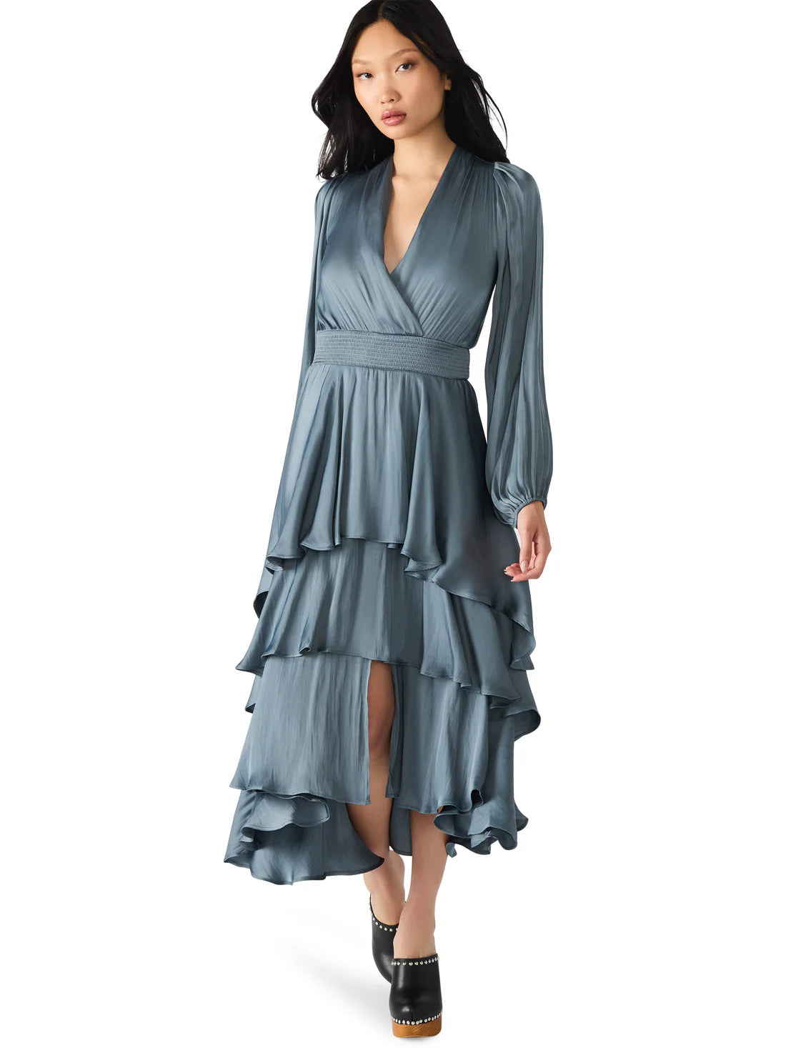 Woman wearing a blue dress with long sleeves and layered skirt on a white background