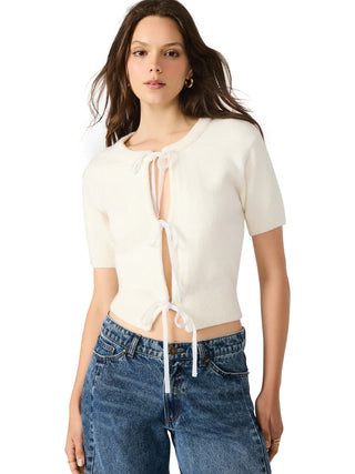 Woman wearing a white lace-up top and blue jeans on a white background