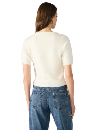 Woman wearing a cream sweater and blue jeans on a white background