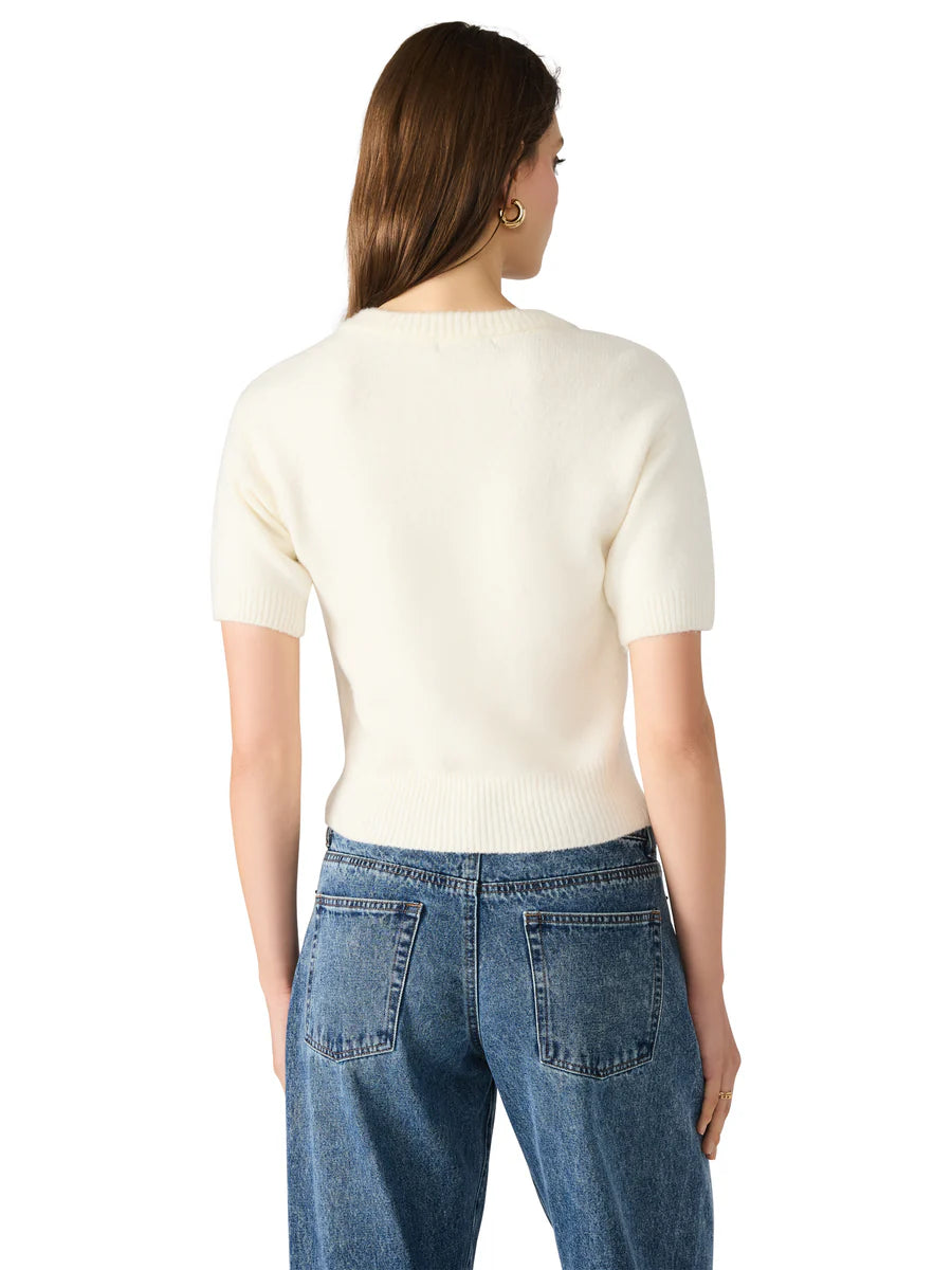 Woman wearing a cream sweater and blue jeans on a white background