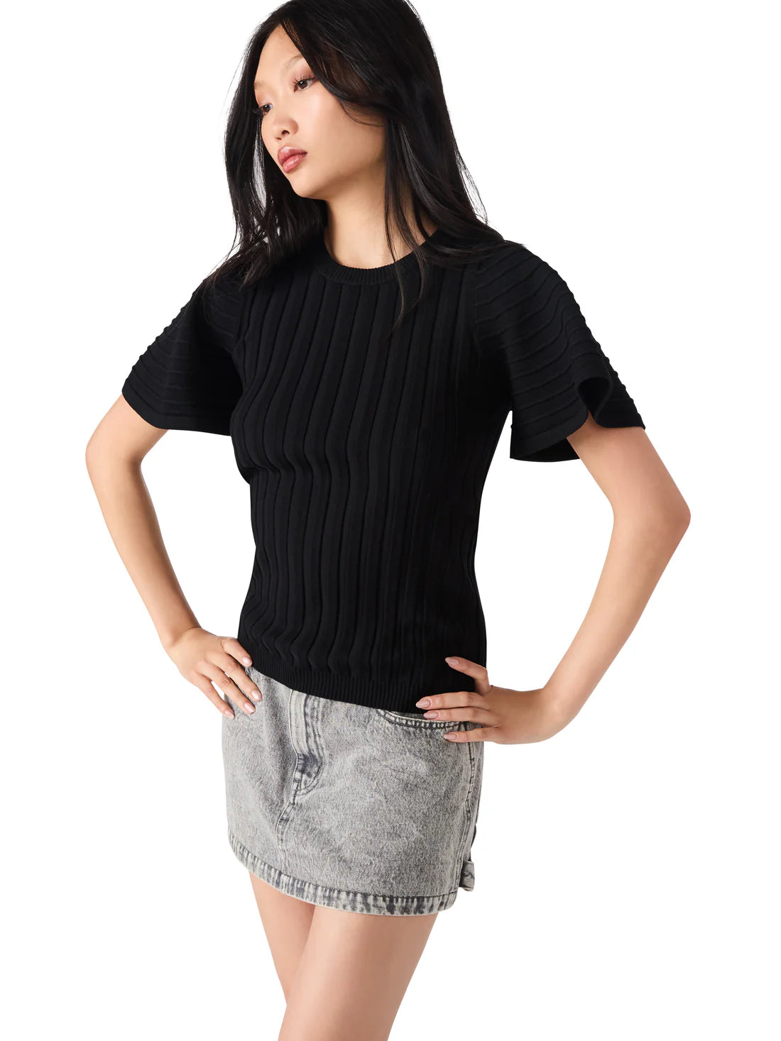Woman wearing a black sweater and denim skirt on a white background