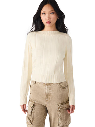 Woman wearing a cream sweater and beige cargo pants on a white background