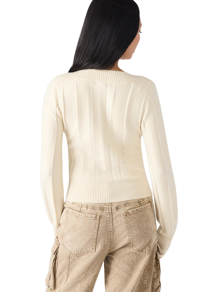 Person wearing a cream sweater and beige pants on a white background