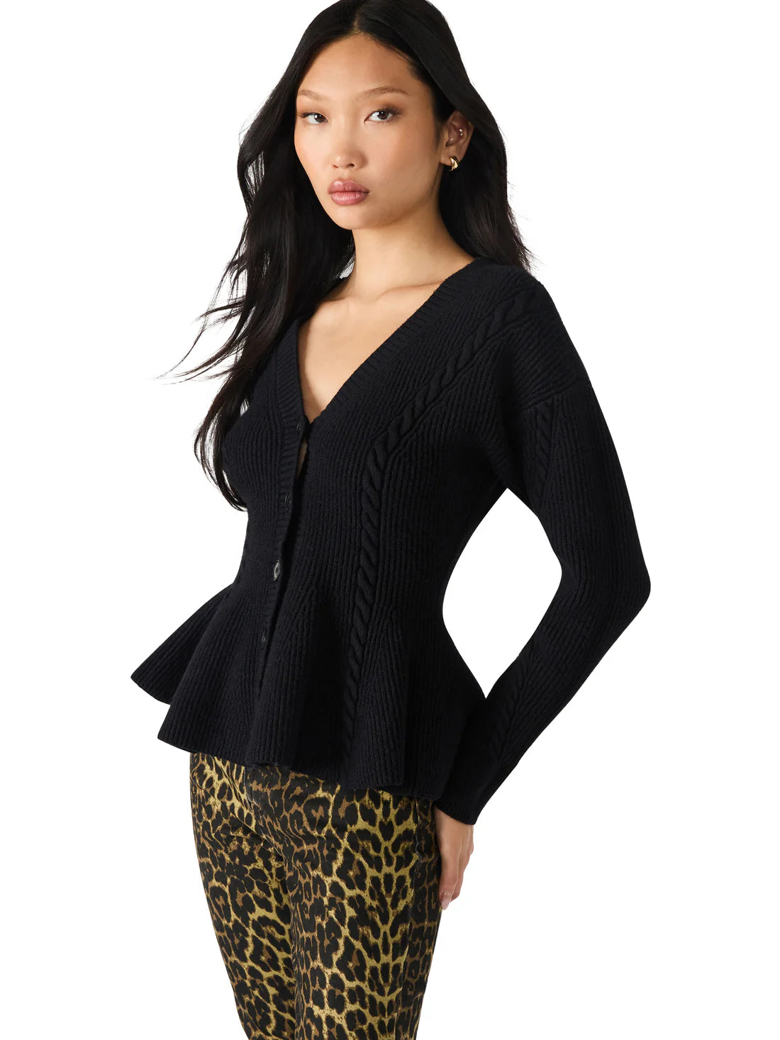 Woman wearing a black peplum top and leopard print pants on a white background