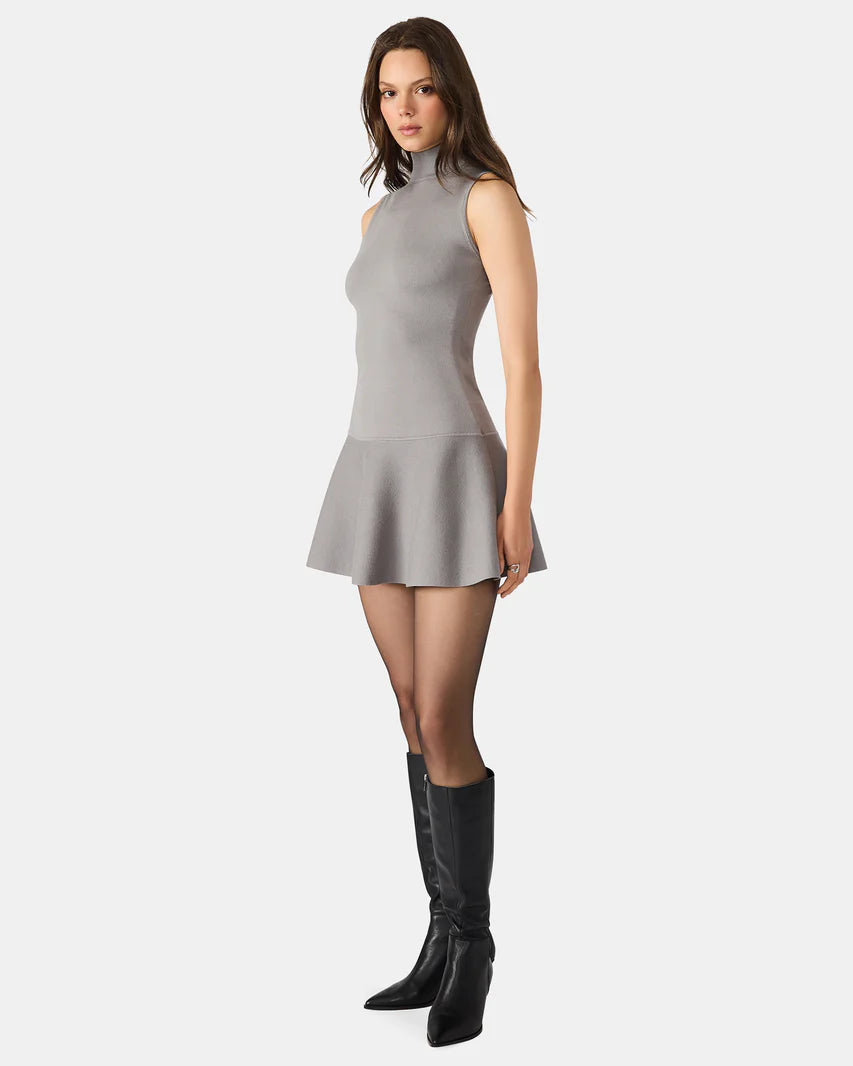 Woman wearing a gray dress with black knee-high boots on a white background