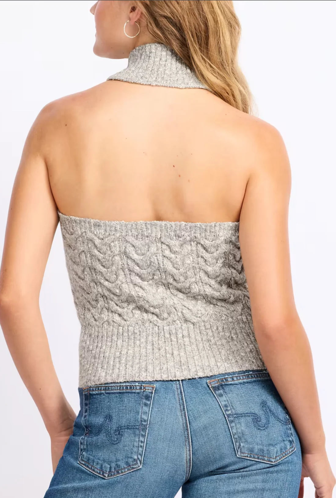 Woman wearing a textured strapless top and blue jeans on a white background