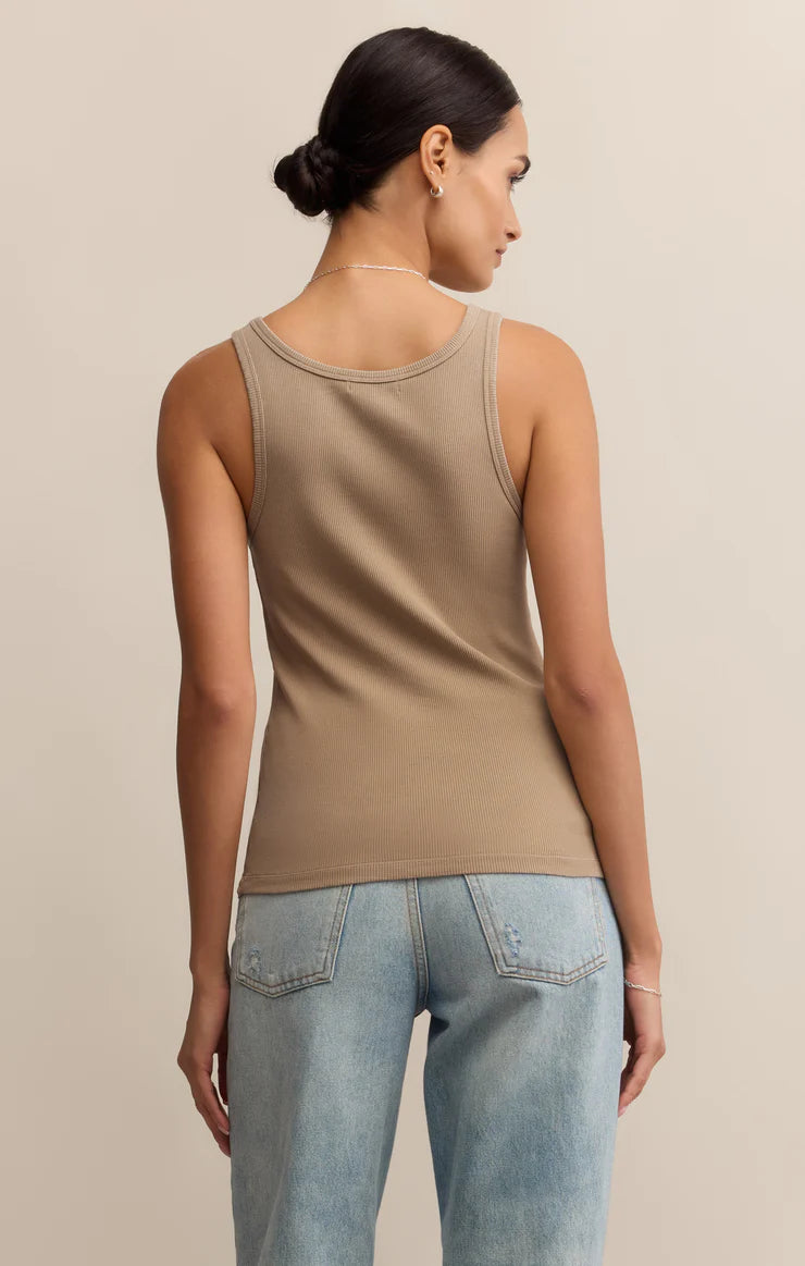 Woman wearing a beige tank top and light blue jeans 