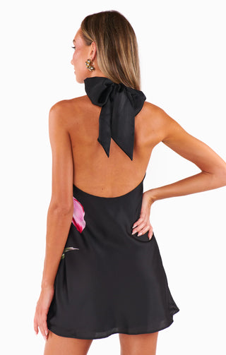 Woman wearing a black halter dress with a bow detail 
