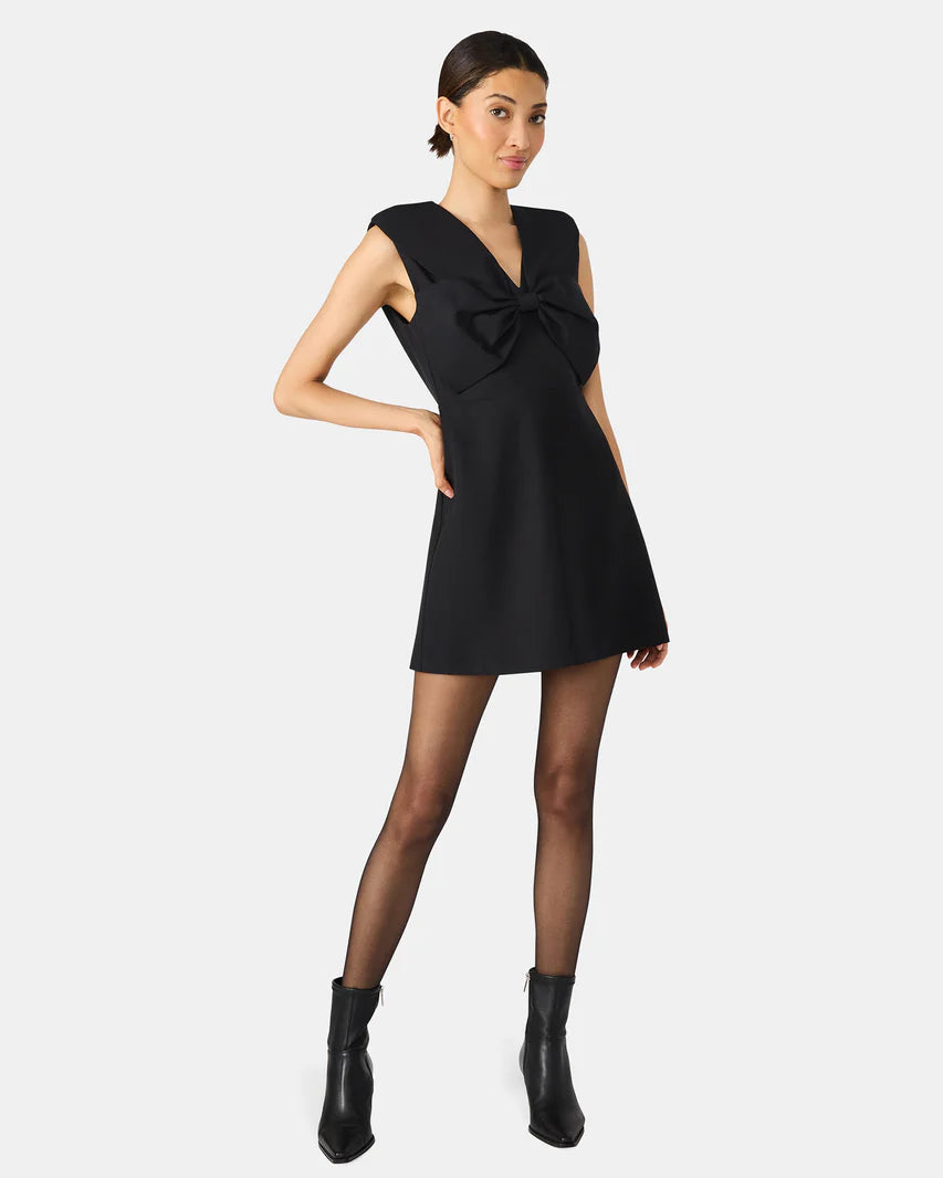 Woman wearing a black sleeveless dress with a bow detail on a white background