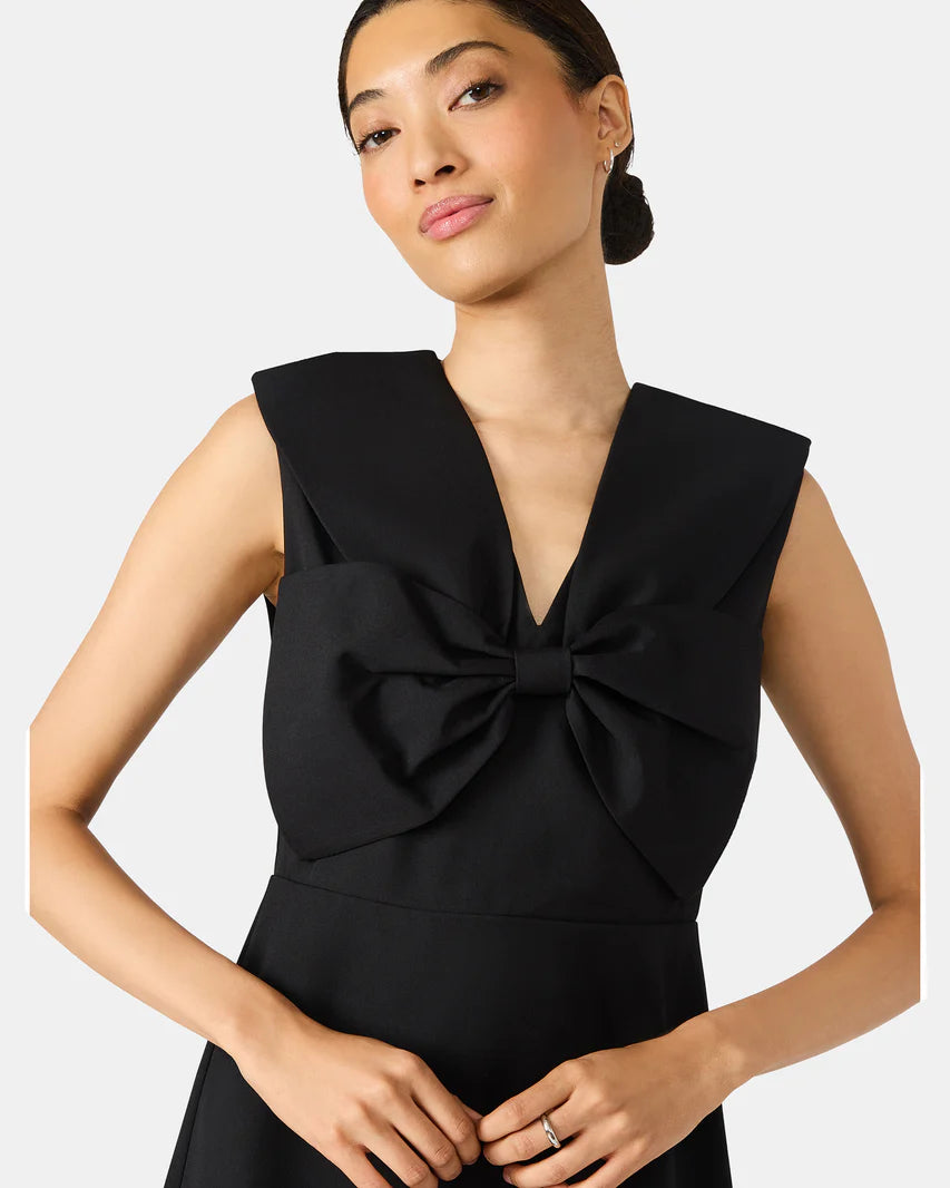 Woman wearing a black dress with a bow detail on a white background
