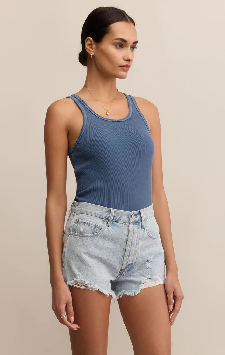 Woman wearing a blue tank top and denim shorts 