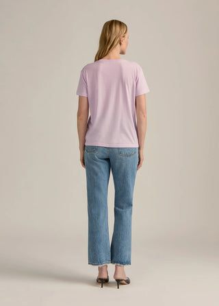 Woman wearing a light pink t-shirt and blue jeans on a beige background