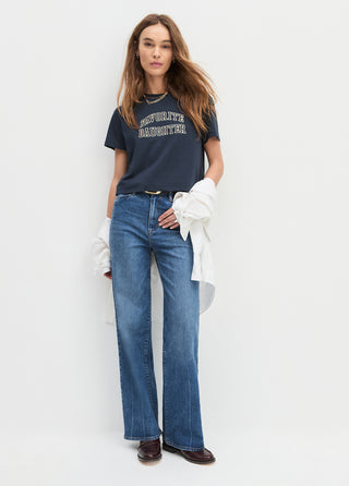 Woman wearing a navy t-shirt and blue jeans on a white background