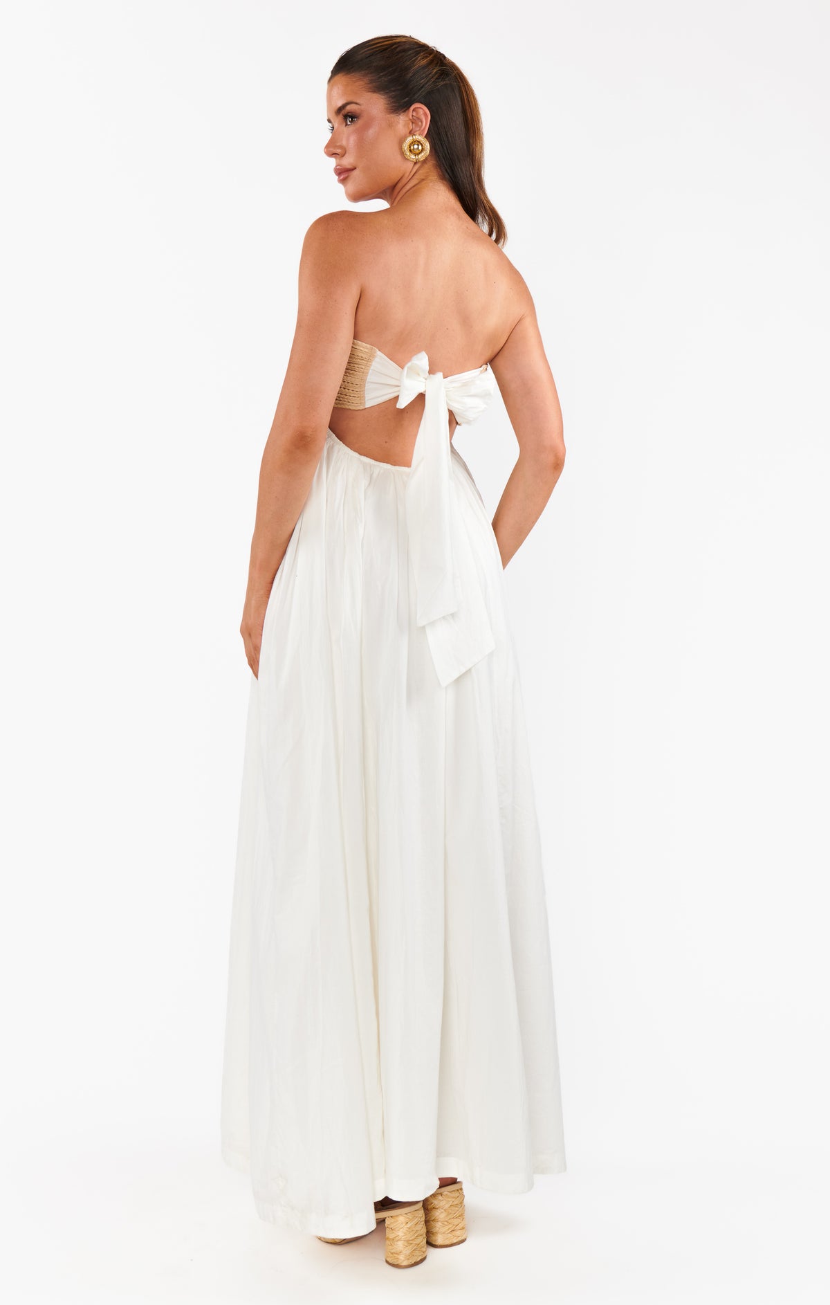 Woman wearing a white backless dress with a bow on a white background