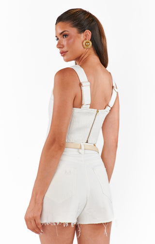 Woman wearing a white denim romper with thin straps on a white background
