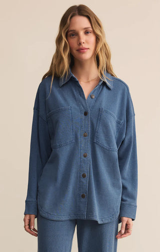 Woman wearing a blue denim shirt against a beige background