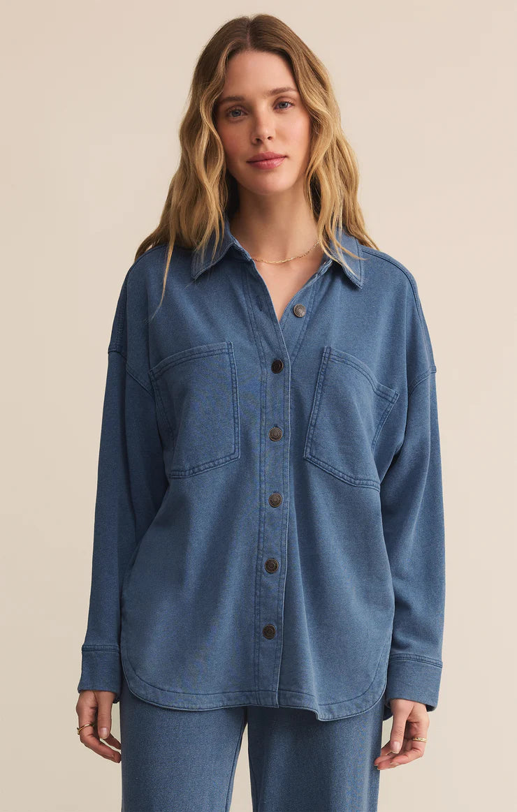 Woman wearing a blue denim shirt against a beige background