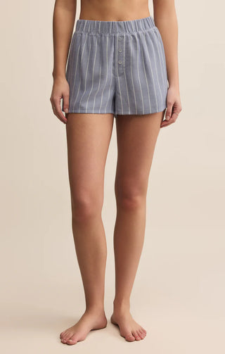 Person wearing blue striped shorts on a beige background