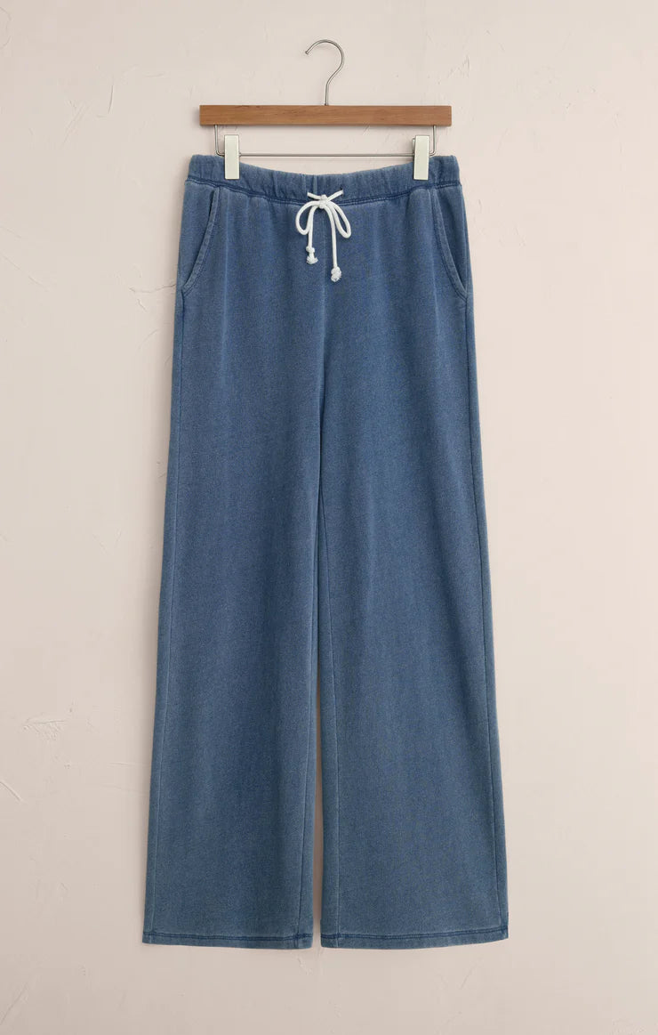 Blue wide-leg pants with a drawstring on a hanger against a beige background