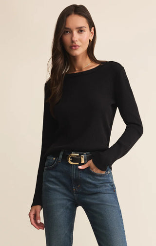Woman wearing a black sweater and blue jeans on a beige background