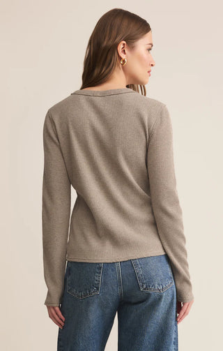 Woman wearing a beige sweater and blue jeans on a beige background
