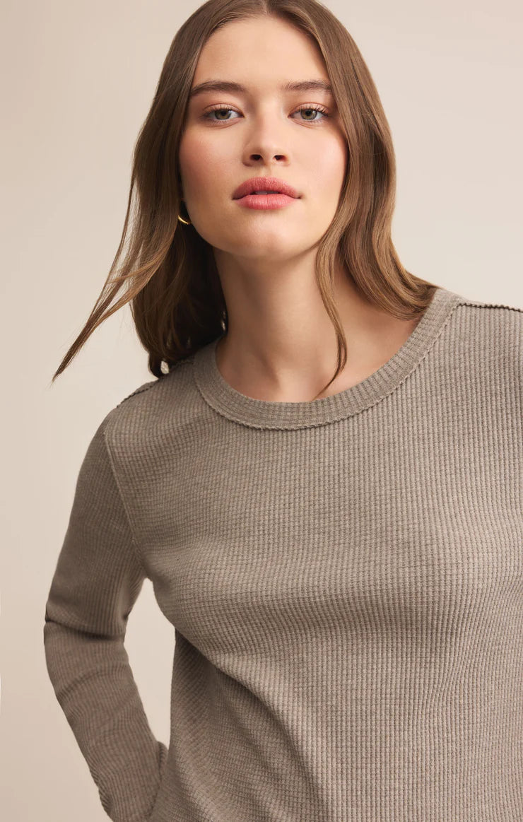 Woman wearing a beige sweater against a neutral background