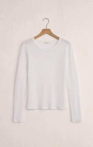 White long-sleeve shirt on a wooden hanger against a light beige background