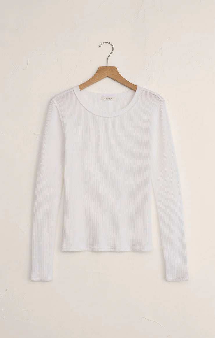 White long-sleeve shirt on a wooden hanger against a light beige background