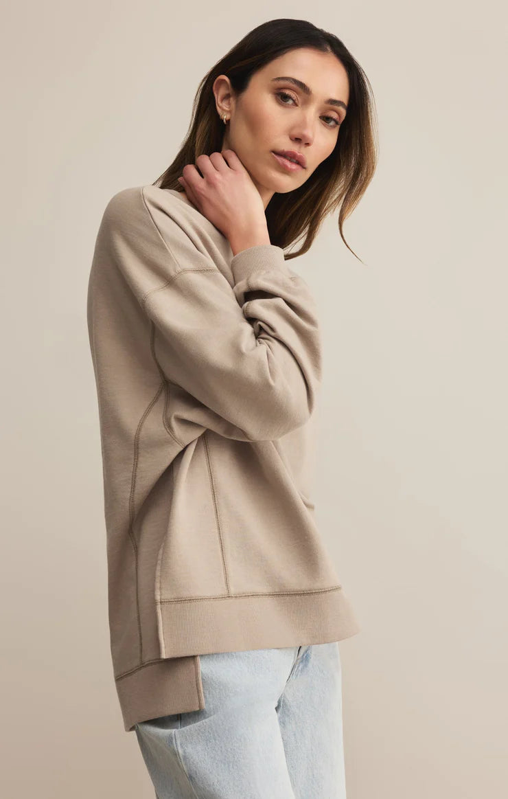 Woman wearing a beige hoodie against a plain background