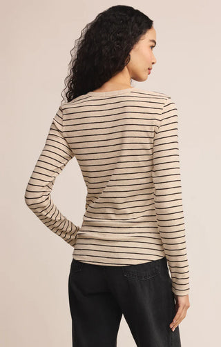 Woman wearing a striped long-sleeve top against a beige background