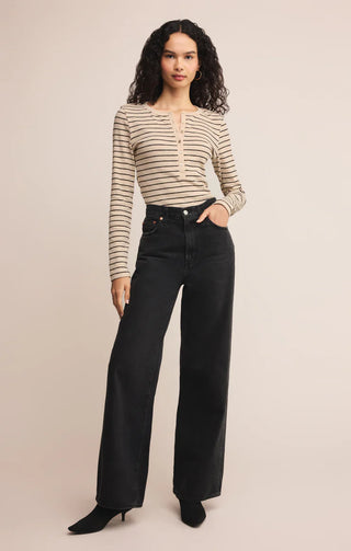 Woman wearing a striped shirt and black pants on a beige background