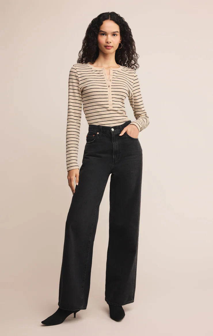 Woman wearing a striped shirt and black pants on a beige background