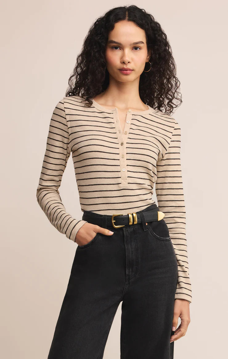 Woman wearing a striped long-sleeve top and black pants on a beige background