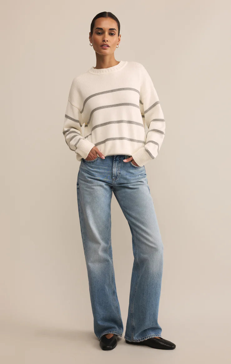 Person wearing a striped sweater and jeans on a beige background