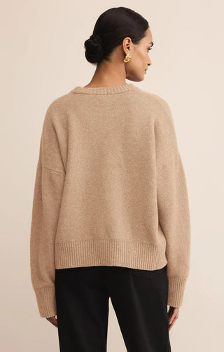 Woman wearing a beige sweater against a plain background