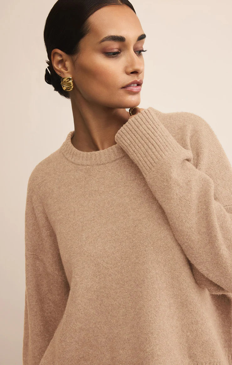 Woman wearing a beige sweater against a neutral background