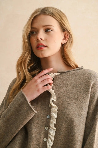 Woman wearing a brown cardigan with lace trim against a beige background