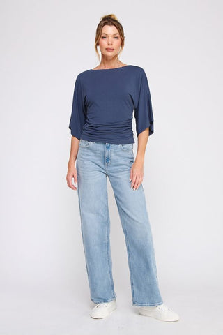 Woman wearing a blue top and light blue jeans on a white background
