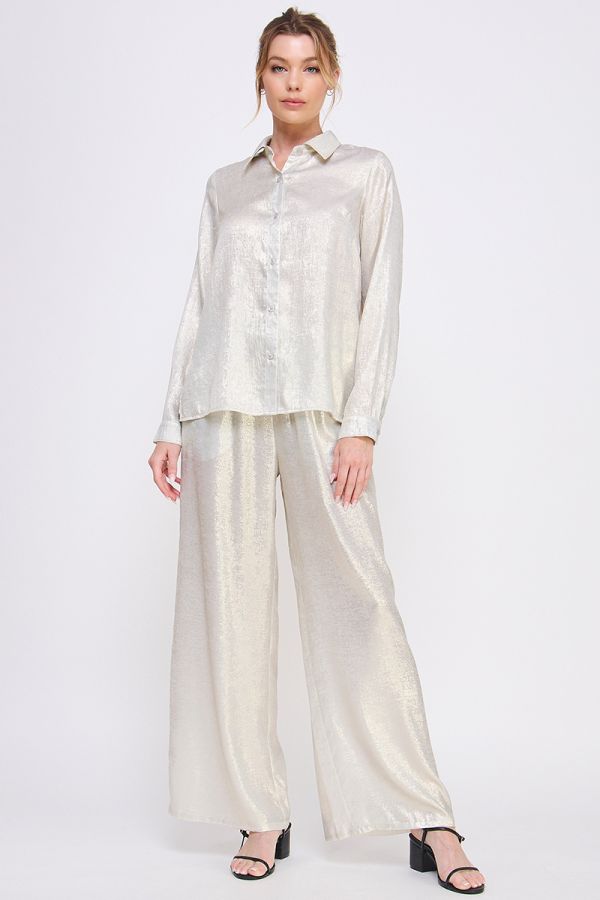 Woman wearing a light-colored blouse and wide-leg pants on a white background