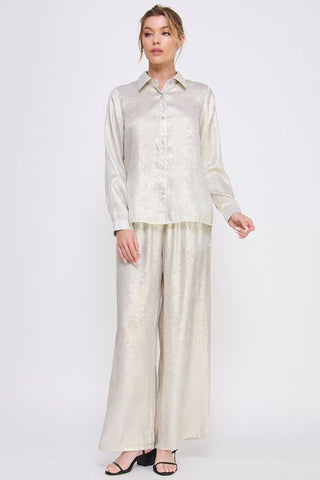 Woman wearing a light-colored shirt and wide-leg pants on a white background