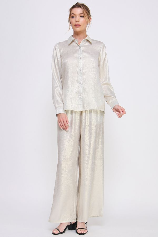 Woman wearing a light-colored shirt and wide-leg pants on a white background